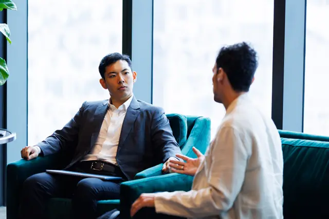 Two guests in conversation on a sofa above the city